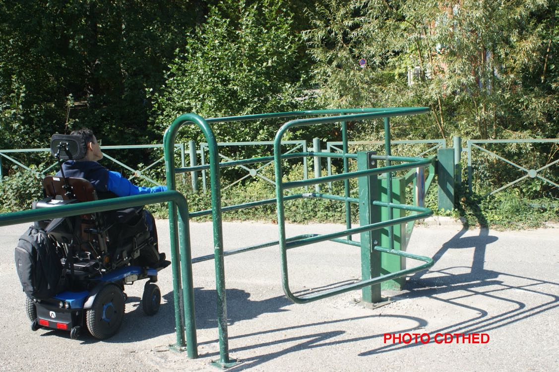 Une personne en fauteuil roulant bloquée par la chicane mobile du parc Forezan